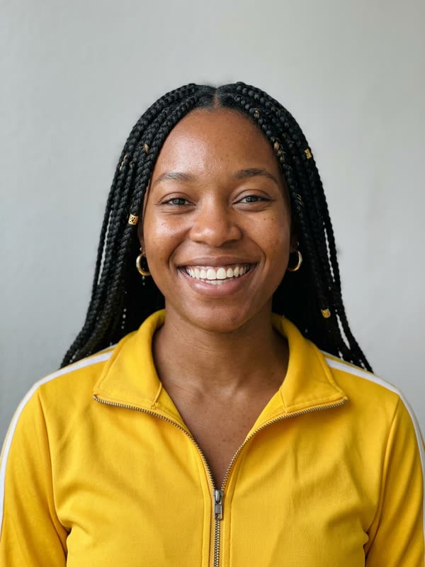 Input photo: fictional woman with long black box braids in a yellow track jacket